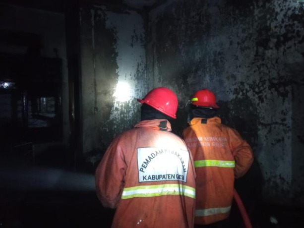 SEDIKIT OKSIGEN: Petugas Damkarla berupaya memadamkaN api yang mebakar toko bangunan Sumber Makmur. (Ist/Radar Gresik)