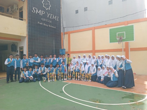 PANEN PRESTASI : Kepala SMP YIMI Ainun Na’im bersama siswanya memamerkan berbagai piala dan medali yang diperoleh dalam satu semester. (Riri/Radar Gresik)