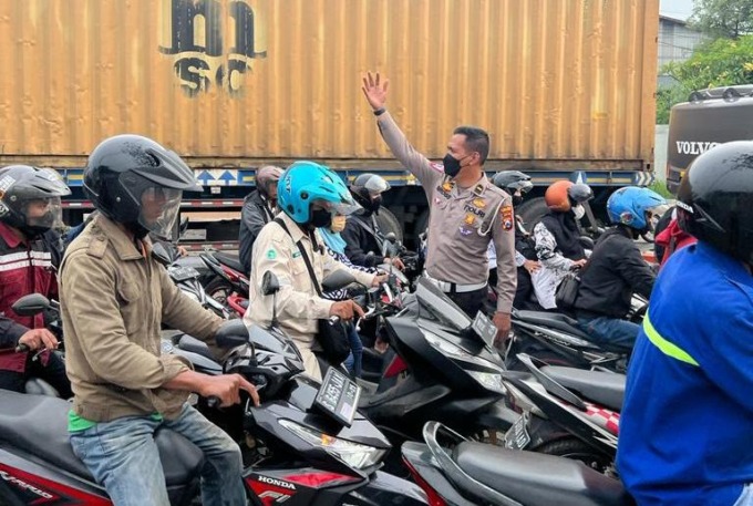 ATUR LALIN: Kanit Turjawali Satlantas Polres Gresik Ipda Bross Tito Dharmawan mengatur kemacetan di Jalan Raya Duduksampeyan dikarenakan ada perbaikan jalan, Kamis (2/2). (Yudhi/Radar Gresik)