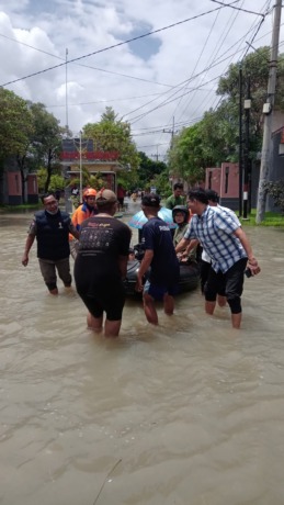 BERI PERHATIAN: Anggota Komisi III DPRD Gresik Abdullah Hamdi saat membantu melakukan evakuasi warga lansia dan bumil di Perumahan Omah Indah Menganti. 9ISTIMEWA/RADAR GRESIK)