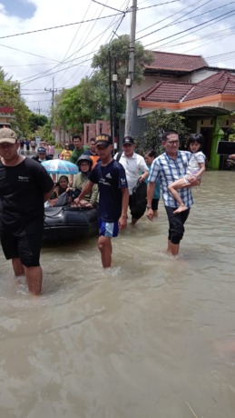 EVAKUASI: Anggota Komisi III DPRD Gresik Abdullah Hamdi saat membantu petugas BPBD melakukan evakuasi warga lansia dan bumil. (istimewa/radar gresik)