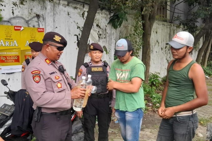 DIAMANKAN: Kasatsamapta Polres Gresik Akp Sugeng saat menunjukan miras yang di amankan dari jok motor milik FD waega Tulangan, Sidoarjo di Jalan Raya Veteran, Kecamatan Kebomas.  (istimewa/radar gresik)