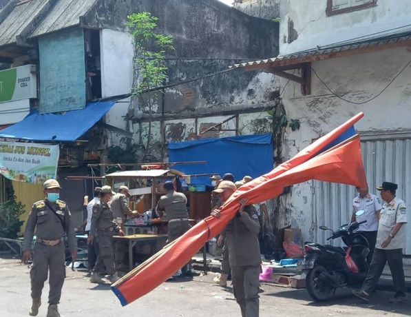 TINDAK TEGAS : Puluhan Personil Satpol PP Pemkab Gresik mengangkut lapak milik PKL Pasar Bandeng yang tidak mau pindah sekalipun event tersebut sudah bubar (FIRMANSYAH/RADAR GRESIK)
