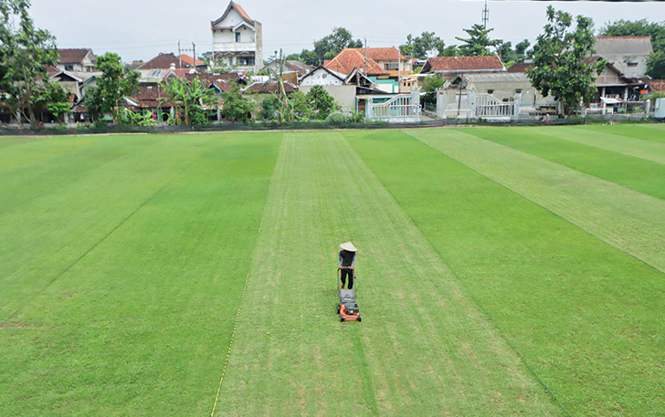 SUDAH MULUS: Pekerja memangkas rumput saat revitalisasi Lapangan Kampung Sewu, Kecamatan Jebres, beberapa waktu lalu. Lapangan Kampung Sewu juga akan dicek FIFA.