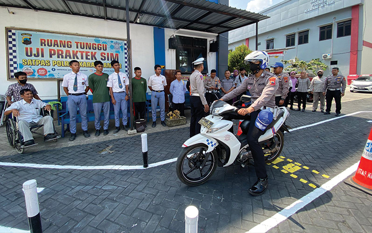 Petugas Satlantas Polres Karanganyar saat memberikan contoh dalam uji praktik SIM C dengan lintasan baru berbentuk huruf S, Senin (7/8).
