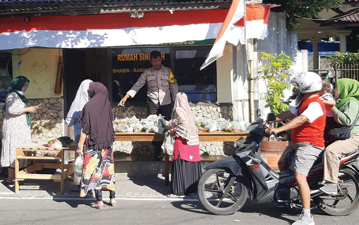 DEKAT WARGA: Sarjono melayani masyarakat mengambil paket bahan sayur gratis di rumah singgah bhabinkamtibmas di Kemlayan, Serengan.