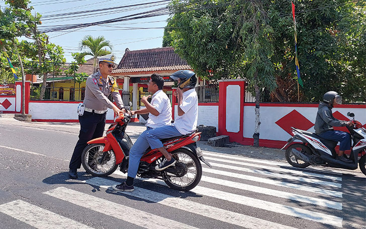 MELANGGAR: Siswa SMA tidak mengenakan helm di depan SMPN 4 Mojosongo pada Selasa (5/9).