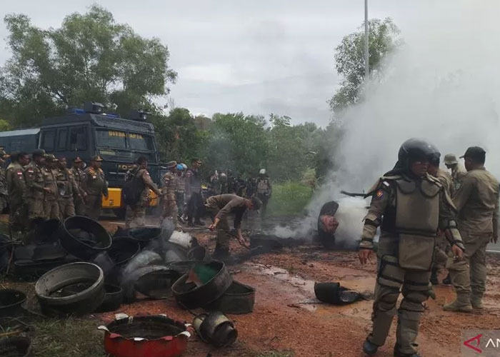 Petugas gabungan membersihkan tumpukan ban yang dibakar warga di lokasi bentrokan di Rempang, Batam.