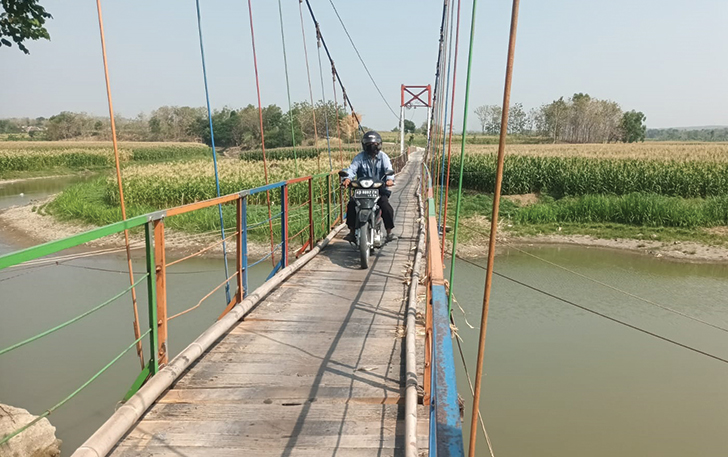 AKSES VITAL: Seorang warga mengendarai sepeda motor, melintas di atas Jembatan Braholo yang menghubungkan Desa Bawu dan Klewor, Kecamatan Kemusu, kemarin (8/10).