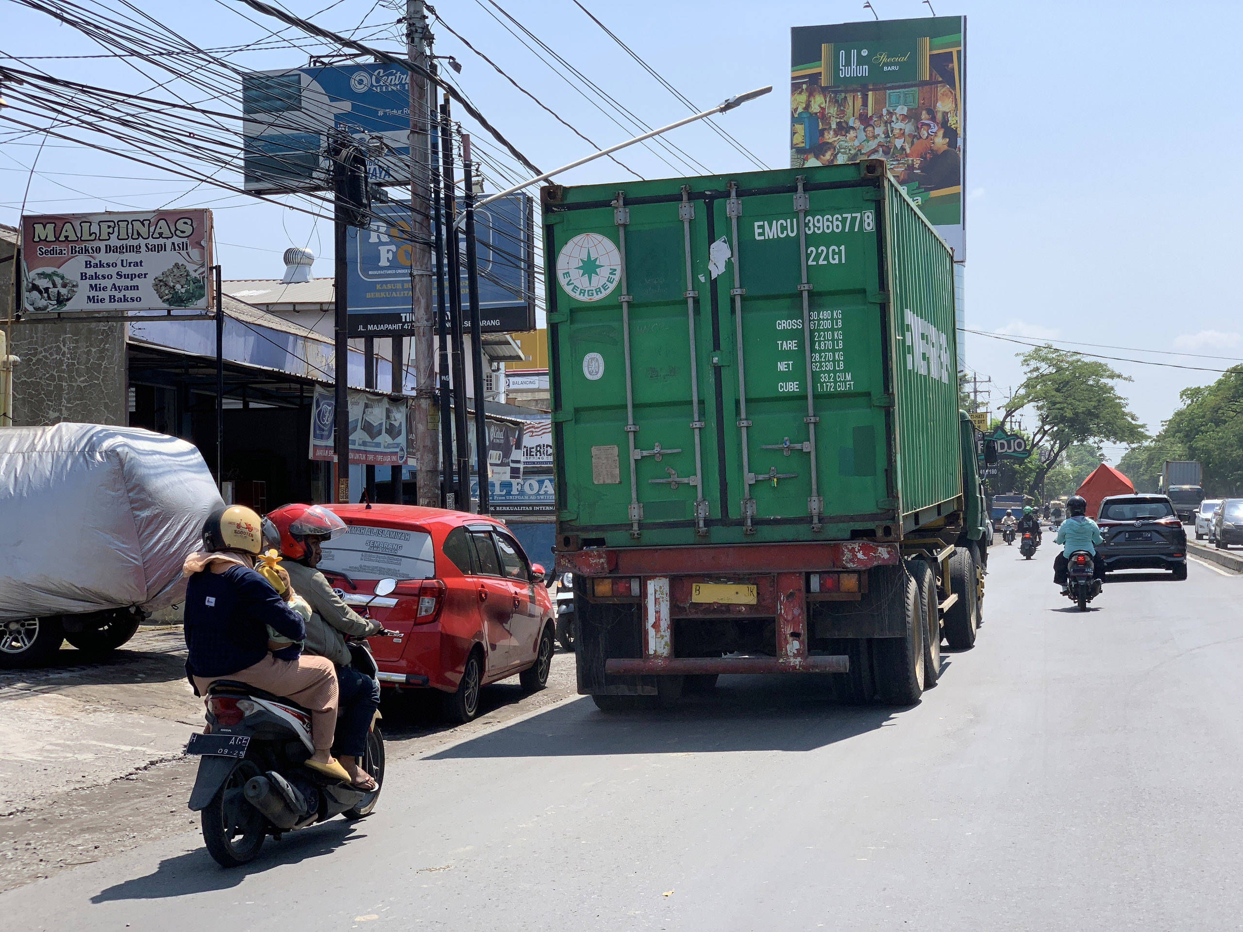 Pengendara sepeda motor berjalan tepat berada di belakang truk besar. Posisi ini sangat membahayakan.
