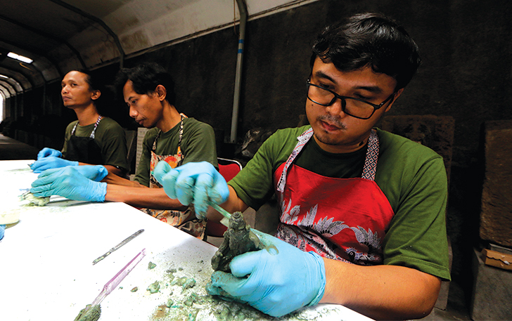 BAHAN ALAMI: Tim Museum Radya Pustaka dibantu mahasiswa membersihkan arca perunggu kemarin (21/11).