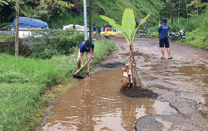 TAK KUNJUNG DIPERBAIKI: Sejumlah warga di Dusun Cetho, Desa Gumeng, Kecamatan Jenawi, Karanganyar, nekat menanam pohon pisang dan menguruk jalan dengan material seadanya, Kamis (7/12).