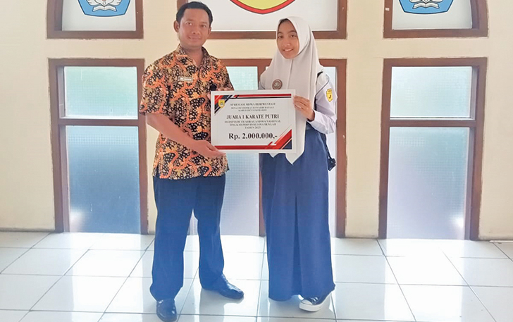 MEMBANGGAKAN: Pejabat Fungsional Dinas Pendidikan dan Kebudayaan Kabupaten Sukoharjo Mulyadi menyerahkan apresiasi siswi SMPN 1 Kartasura kepada Luthfi Nur Prasetya, kemarin.