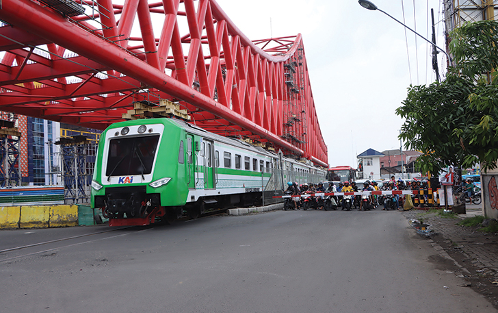 TERTIB: Pengendara motor menunggu kereta lewat saat berada di Jembatan Layang Joglo, kemarin.