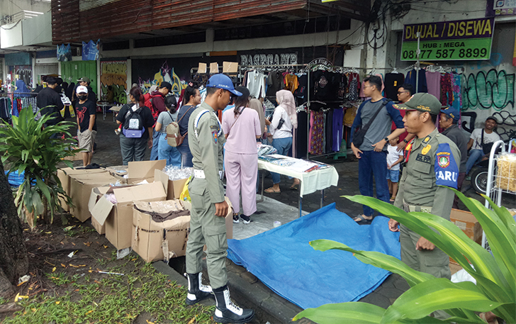 BERI ARAHAN: Petugas Satpol PP Kota Solo memberi teguran ke pedagang yang menggelar tikar di momen CFD, kemarin.