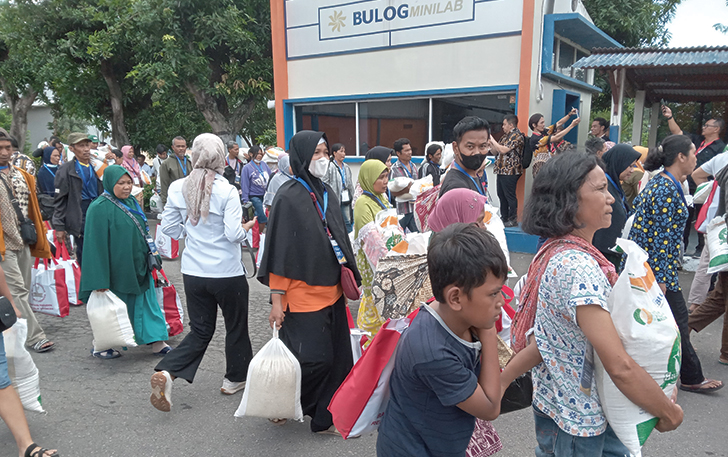 BERBONDONG: Ratusan warga menenteng paket bantuan pangan di halaman Gudang Bulog Telukan, Kecamatan Grogol, Kabupaten Sukoharjo, kemarin (1/2).