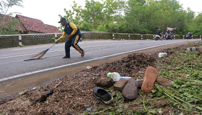 Warga membersihkan jalan yang menjadi lokasi kecelakaan bus pariwisata terguling di Jalan Imogiri-Dlingo, Padukuhan Banyusumurup, Girirejo, Imogiri, Bantul, Kamis (8/2).