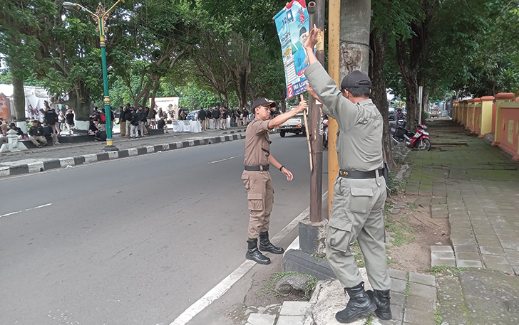 Petugas Satpol PP melepas alat peraga kampanye yang dipasang di kawasan Alun-alun Satya Negara Sukoharjo, Kamis (8/2/2024)