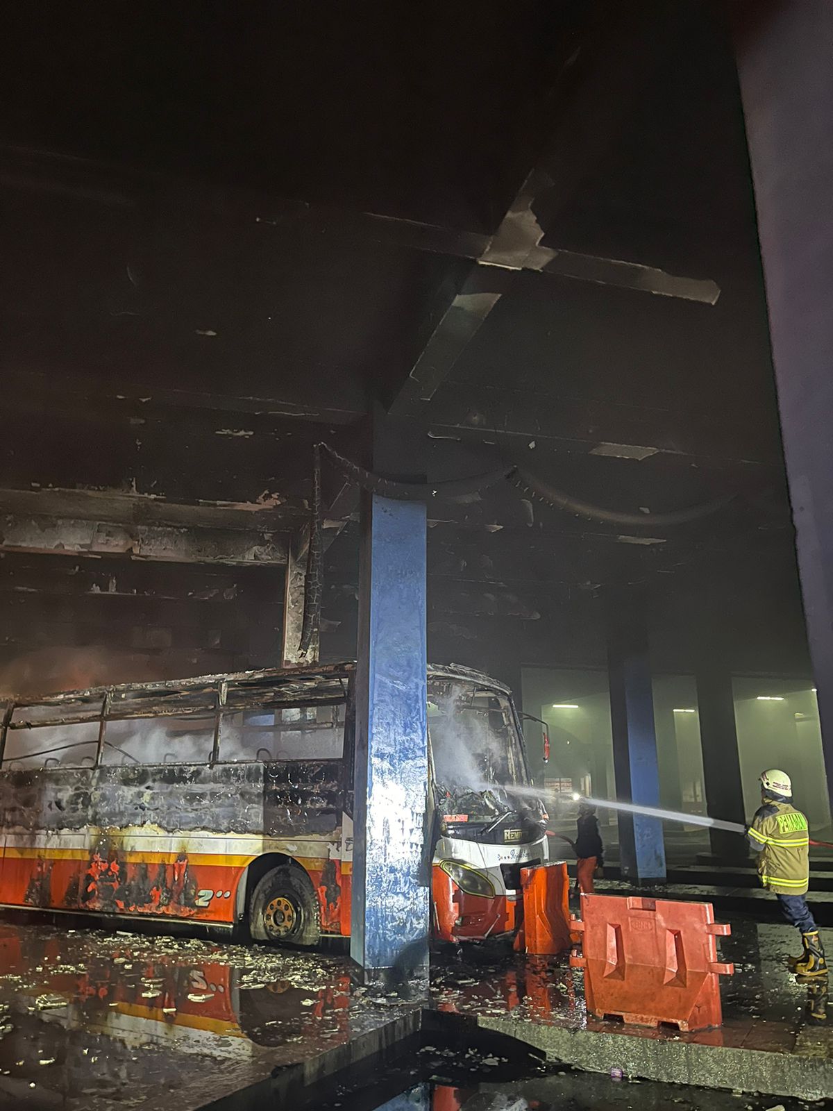 Personel Damkar Kota Solo lakukan pendinginan terhadap bodi Bus Rela yang terbakar di Terminal Tirtonadi, Minggu (11/2/2024) malam.
