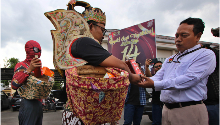 Pemuda berkostum Gatotkaca dan Spiderman memberikan jamu serta vitamin ke KPU Sukoharjo, Senin (12/2).
