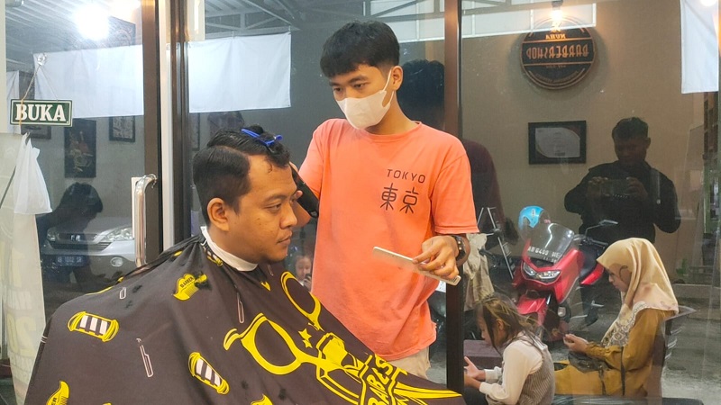 Ulin memangkas rambut pelanggannya di Kecamatan Gemolong, Kabupaten Sragen.
