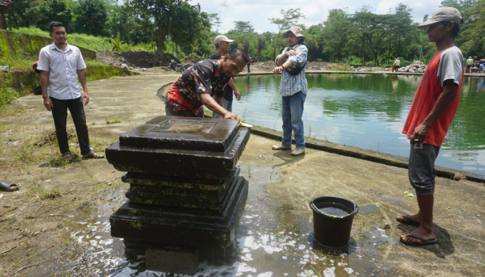 Warga Desa Pondok bersama pegiat cagar budaya saat membersihkan batu yoni di Kawasan Embung Sikajar, Selasa (5/3).