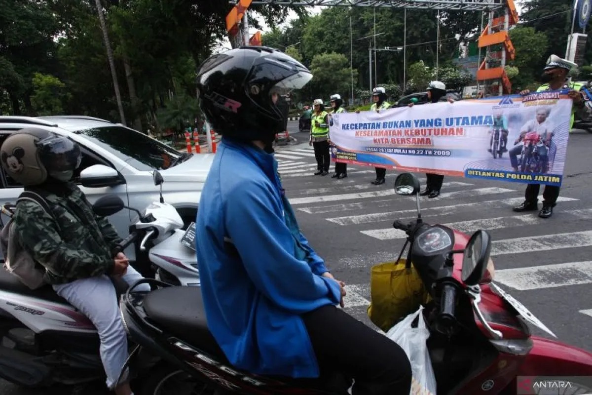 Polantas membentangkan spanduk imbauan kepada pengguna jalan saat sosialisasi keselamatan berlalu lintas di Surabaya, Jawa Timur, Selasa (5/3/2024).