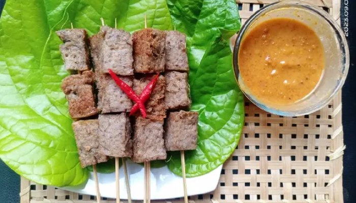 Sate jantung pisang dicocol dengan sambal kacang.