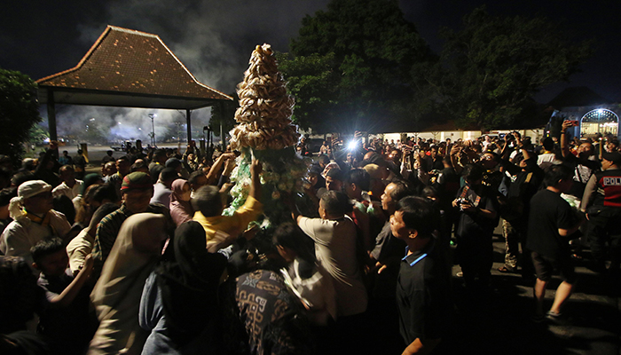 Masyarakat berebut gunungan berisi makanan usai kirab obor di Pura Mangkunegaran, Selasa (9/4/2024).