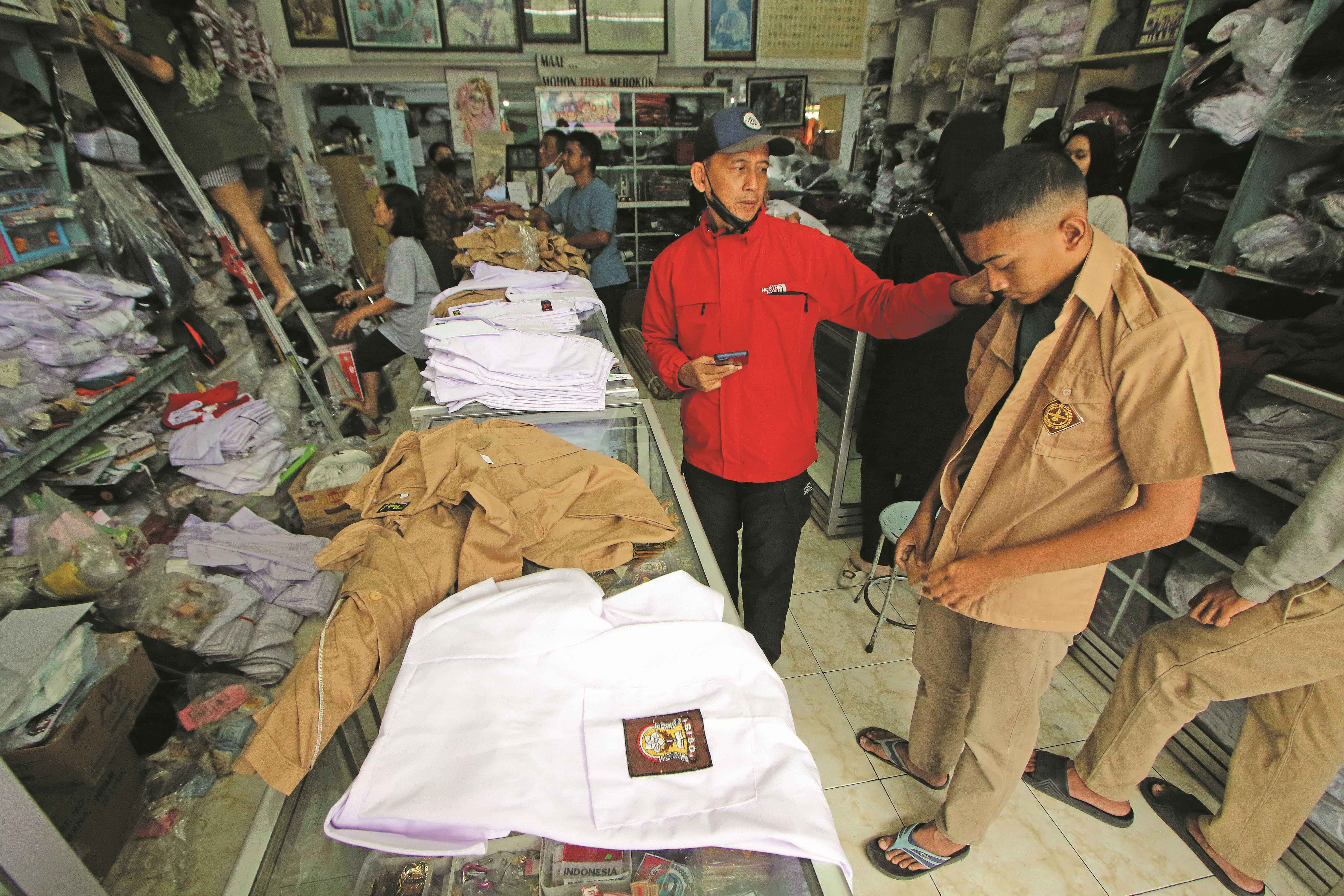 Orang tua siswa menemani anaknya membeli seragam di salah satu toko seragam, belum lama ini.