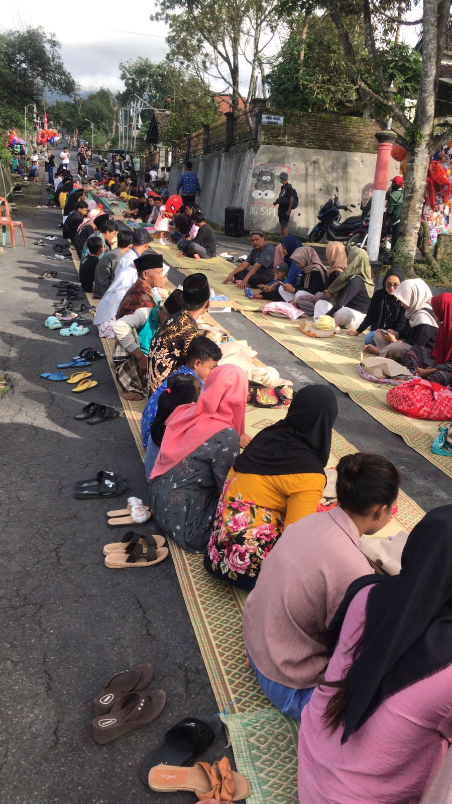 Dimulai dengan kenduri ketupat di tengah jalan beralas tikar. Warga saling bertukar lauk dan pauk, lalu makan bersama.