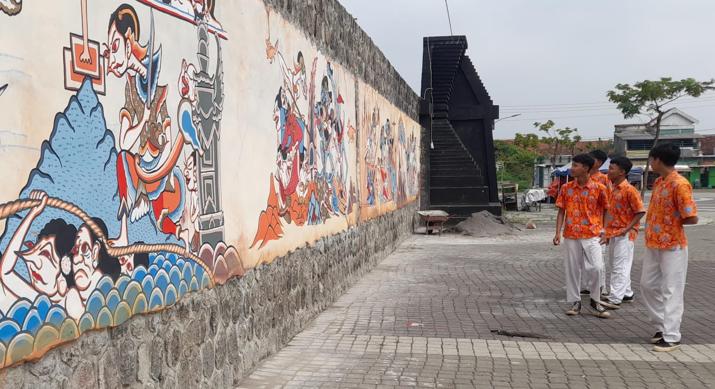 Sejumlah pelajar melihat karya seni wayang beber yang terpampang di tembok Stadion 45 Karanganyar. (Rudi Hartono/Radar Solo)