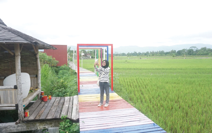 INSTAGRAMABLE: Wisatawan sedang asyik berfoto di atas jalan setapak yang membelah lahan persawahan di kawasan Tirto Mili Desa Pasung, Kecamatan Wedi, Klaten.