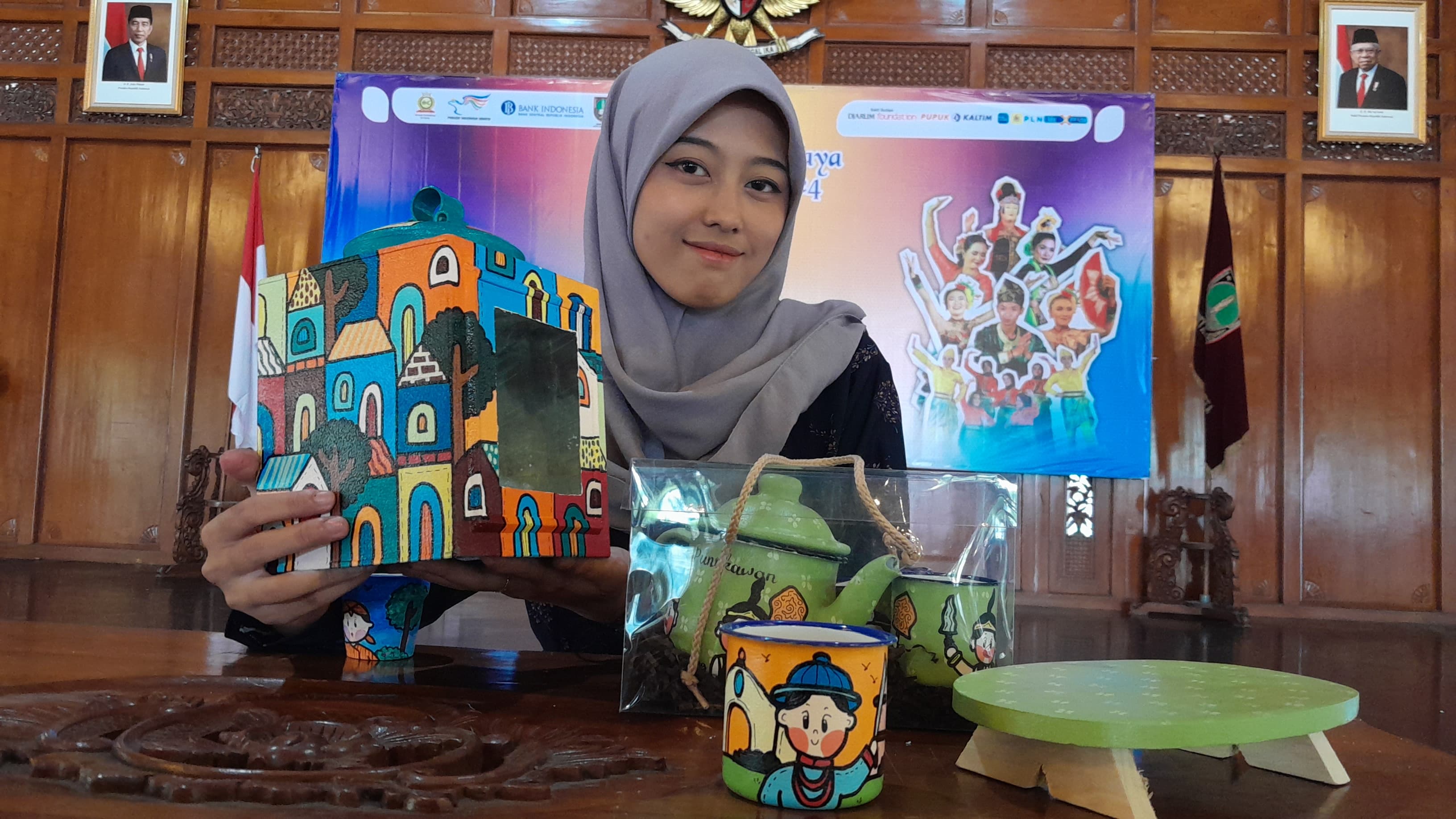 Aulia Putri Cinta memamerkan gelas lukis karyanya yang kini jadi ladang usaha.