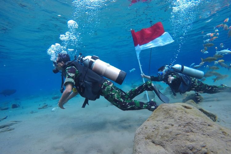 Anggota TNI Kodim Klaten mengibarkan bendera merah putih di dalam air di Umbul Ponggok, Klaten, Jawa Tengah.