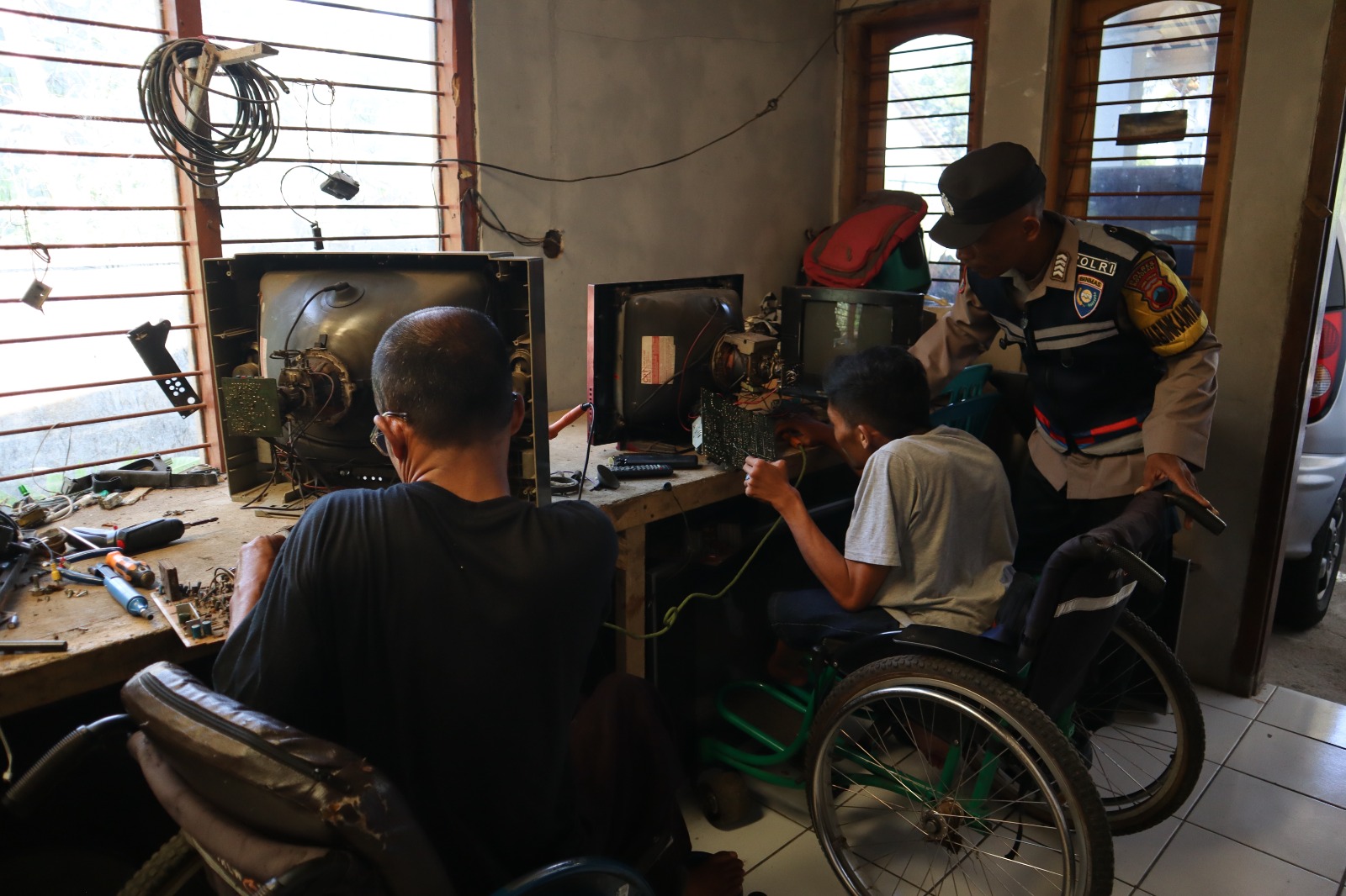 Bripka Marwanto, Bhabinkamtibmas Desa Candi, Ampel, Boyolali mendampingi difabel berlatih memperbaiki televisi.