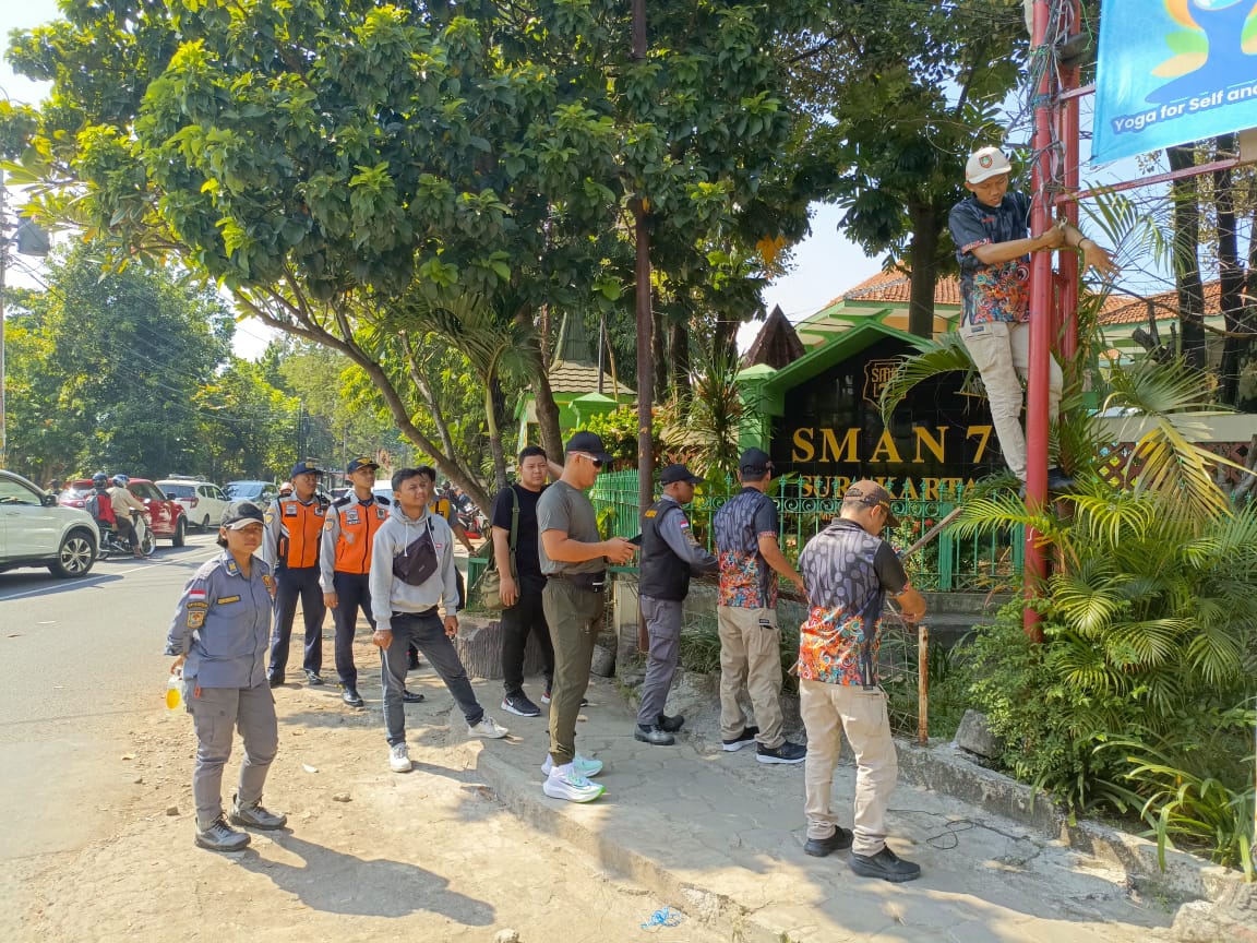 Petugas Bapenda Kota Surakarta memanjat tiang besi untuk mencopot reklame liar.