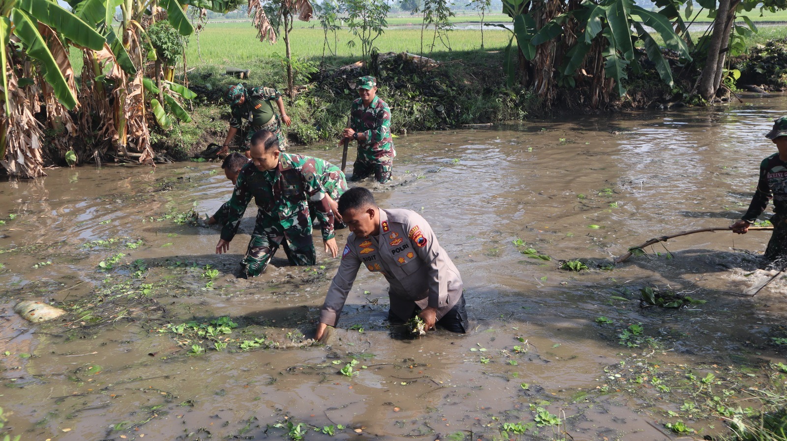 Anggota TNI/Polri bersihkan sampah di saluran irigasi Desa Grajegan, Kecamatan Tawangsari, Sukoharjo, Rabu (10/7).