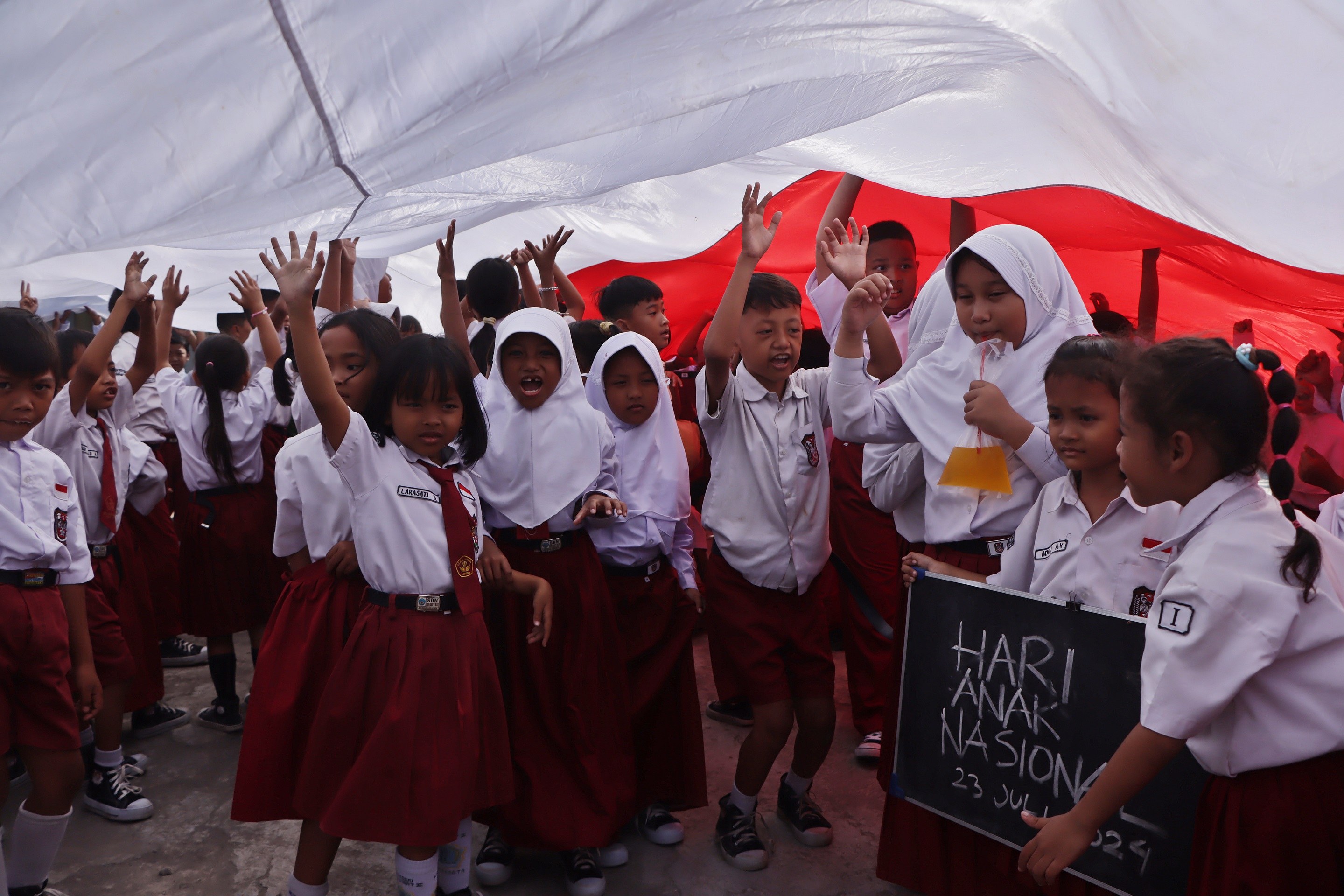 Siswa SDN Nayu Barat I bentangkan bendera raksasa bawa pesan damai di Hari Anak Nasional, Selasa (23/7/2024). (Arief Budiman/Radar Solo)