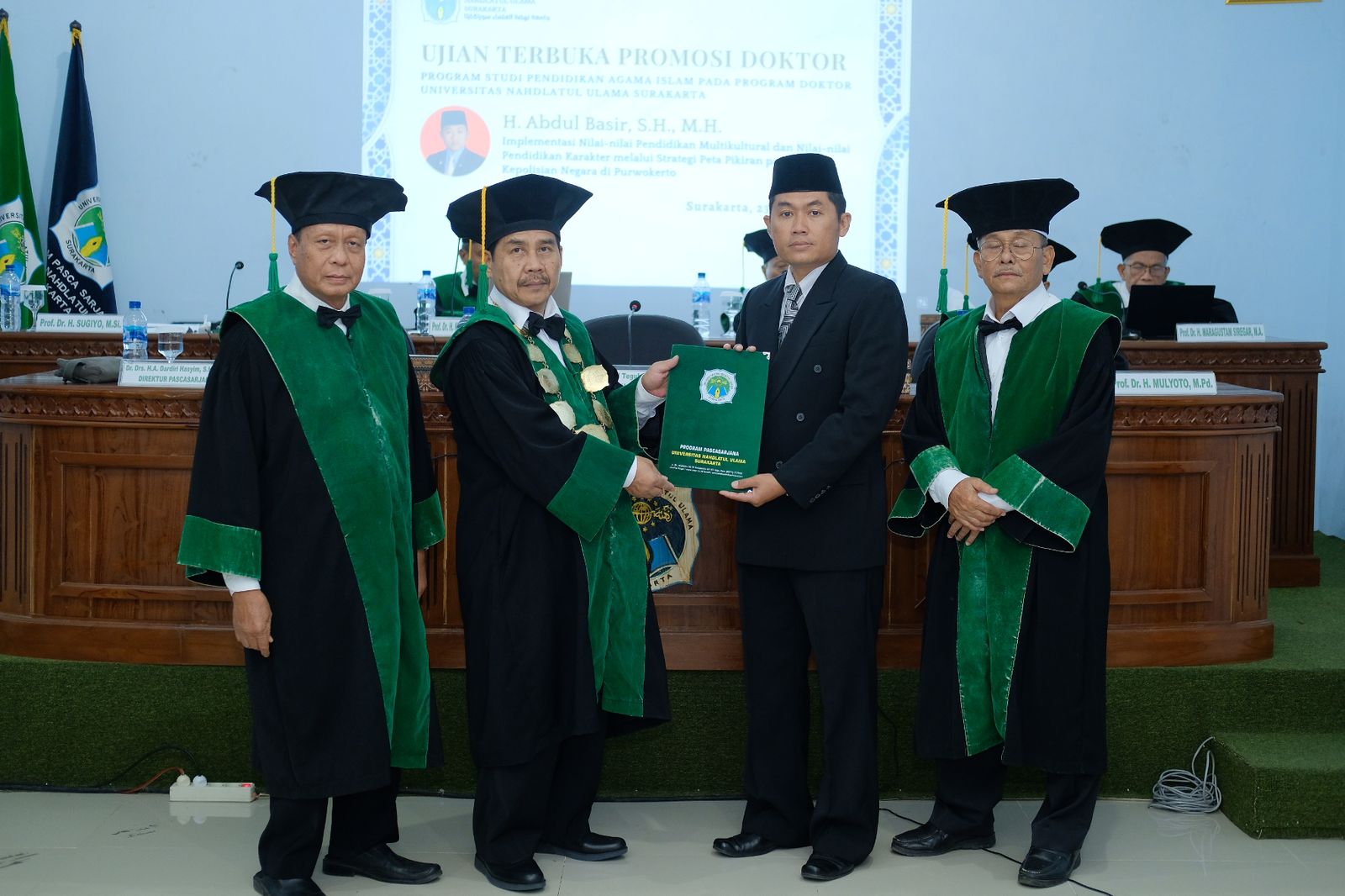 Rektor UNU Surakarta Ahmad Mufrod Teguh Mulyo (kedua dari kiri) menyerahkan ijazah kelulusan doktor kepada Abdul Basyir (kedua dari kanan) di ruang sidang kampus setempat, Selasa (23/7).