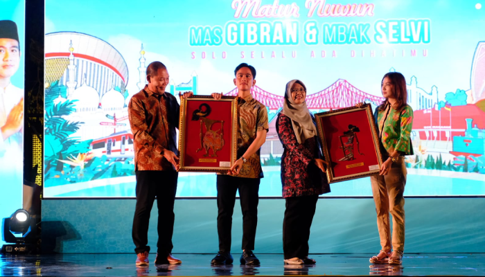 Wakil Presiden Terpilih Gibran Rakabuming Raka dan istri Selvi Ananda menerima hadiah dari Wali Kota Solo Teguh Prakosa saat pisah sambut di Taman Balekambang Solo, Jumat (26/7).