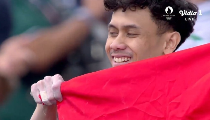 Tangkapan layar atlet panjat tebing Indonesia Veddriq Leonardo memegang bendera Merah Putih setelah sukses raih medali emas pertama untuk Indonesia.