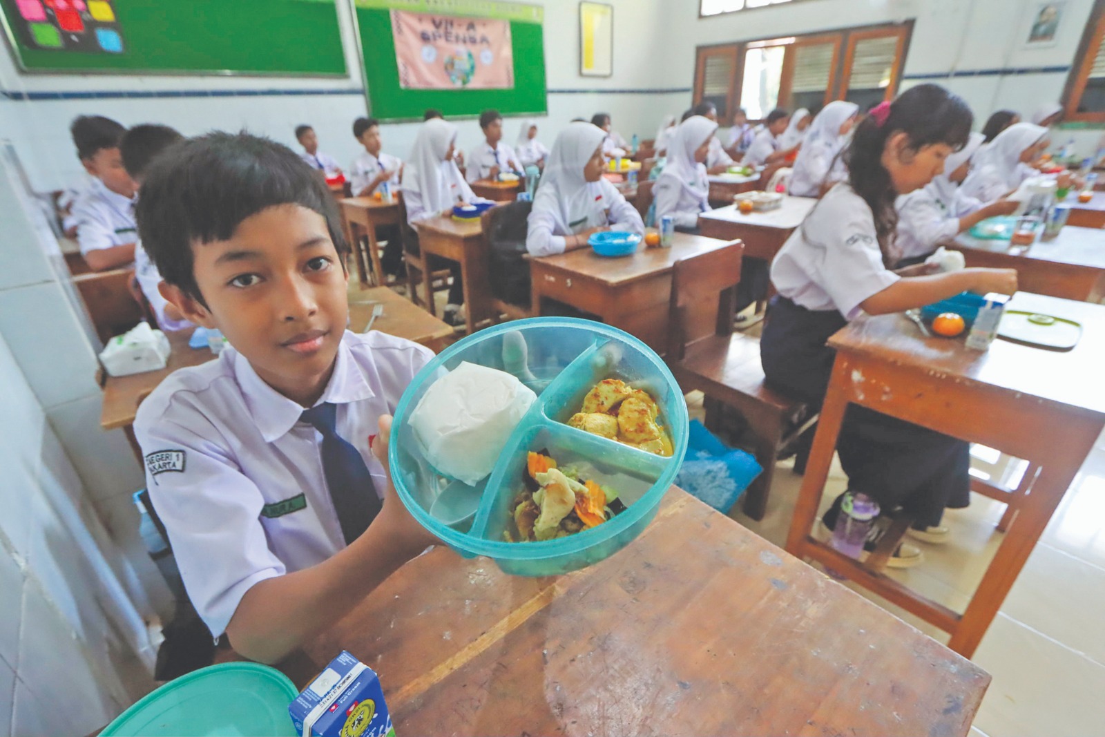 Siswa SMPN 1 Solo tunjukkan menu Makan Bergizi Gratis saat uji coba di kelas, Selasa (17/9).