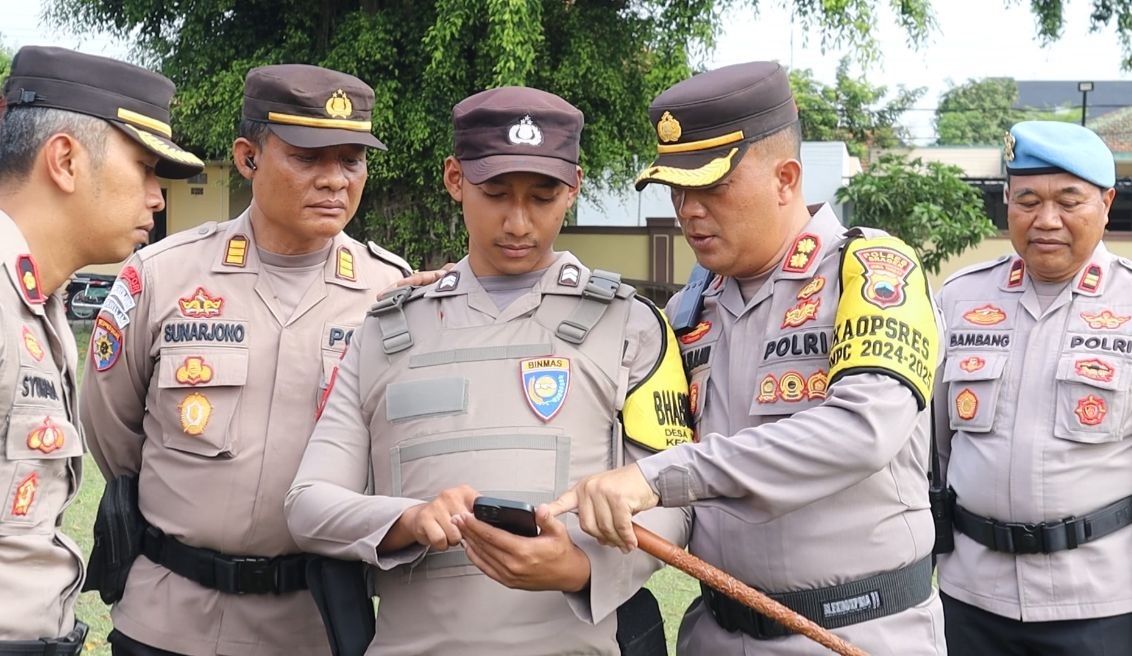 Kapolres Sragen AKBP Petrus Parningotan Silalahi (dua dari kanan) mengecek handphone (HP) anggota usai apel pagi, Senin (4/11/2024). (Ahmad Khairudin/Radar Solo)