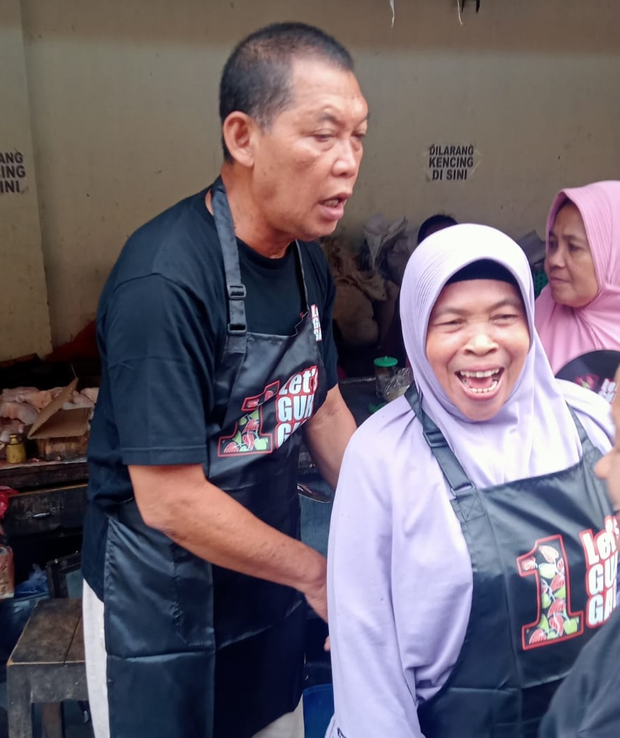 Calon Walikota Solo Teguh Prakosa membantu mengikatkan tali celemek pedagang saat berkunjung ke Pasar Mojosongo, Jumat (15/11/2024).