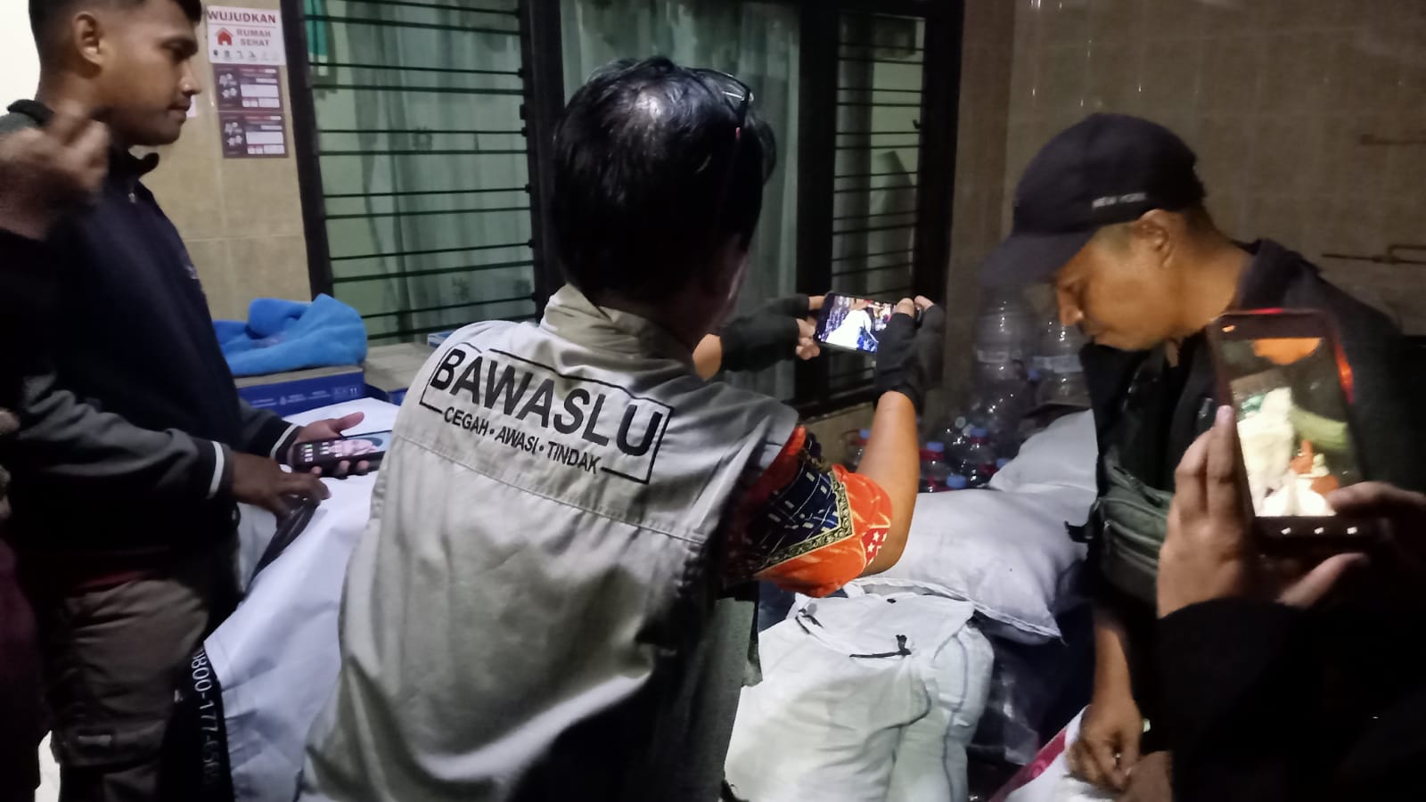 Tim Bawaslu Solo mendokumentasikan tumpukan karung berisi sembako di sebuah rumah kawasan Kelurahan Pucangsawit, Jebres, Kota Solo, Minggu (24/11/2024) malam.