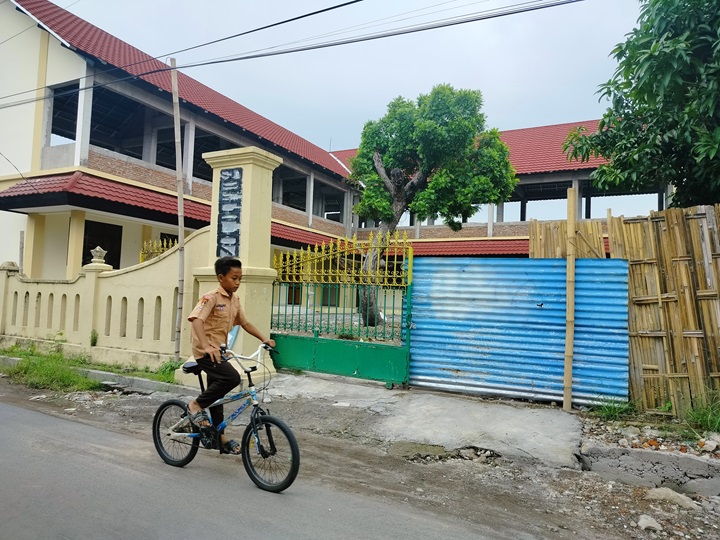 Seorang bocah mengendarai sepeda, melintas di depan proyek pembangunan SDN Begalon di di Jalan Srinarendra, Panularan, Kecamatan Laweyan, Selasa (6/12).