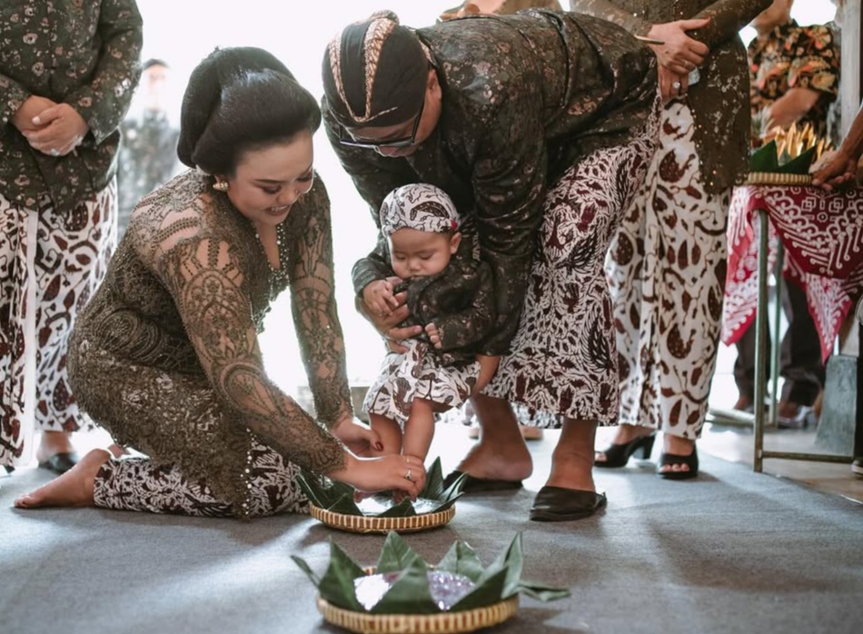 Ilustrasi seorang bayi menjalani prosesi tedhak siten dengan melewati tujuh jadah.
