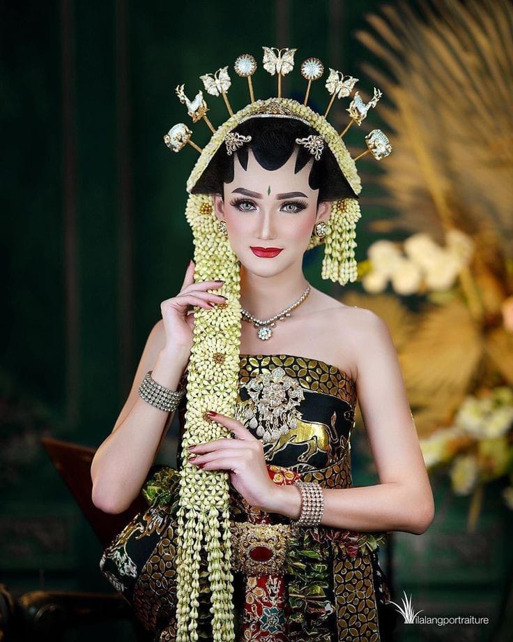 Pengantin mengenakan busana bergaya putri Solo basahan dengan cundul mentul di kepala.