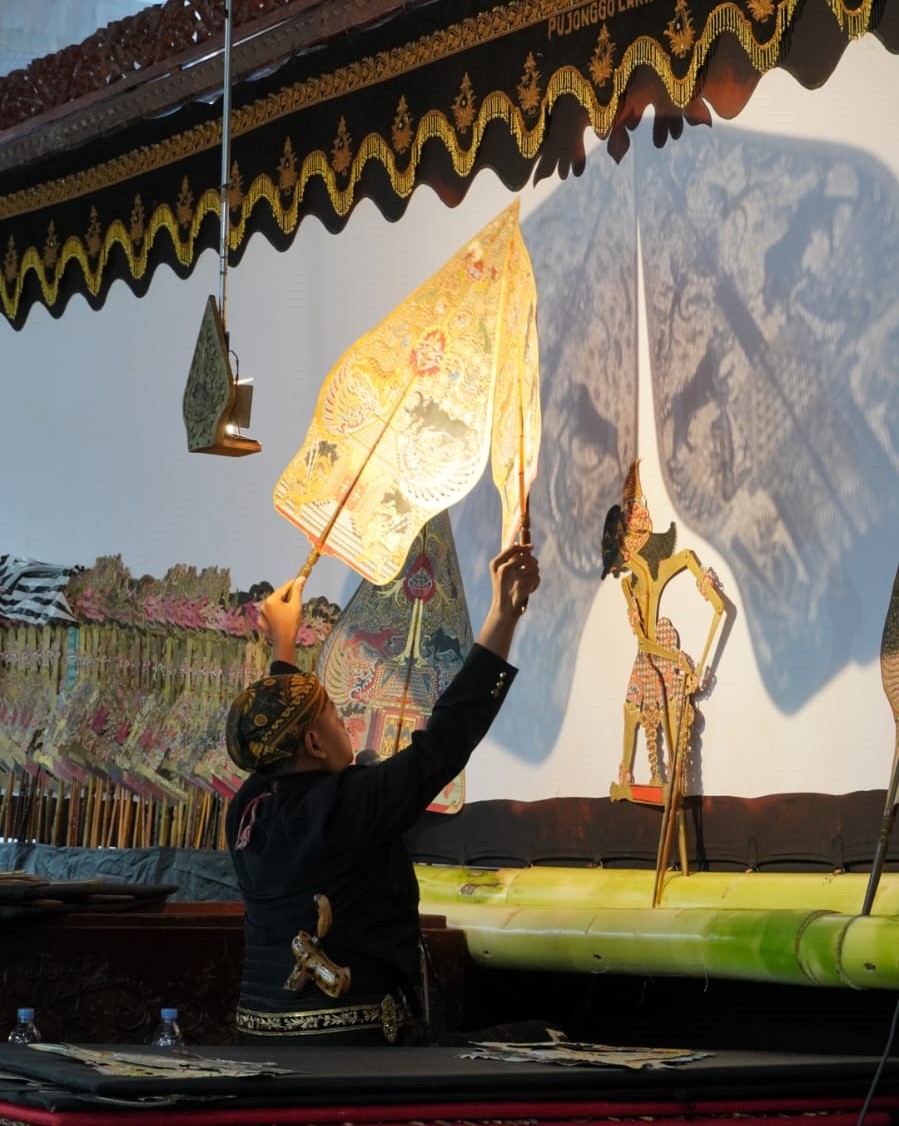 Dalang mengangkat gunungan pada pertunjukan wayang kulit.